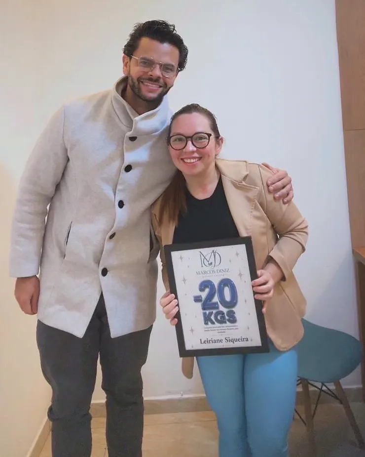 Paciente do Dr. Marcos Diniz recebendo uma placa de resultado