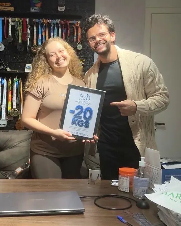 Paciente do Dr. Marcos Diniz recebendo uma placa de resultado