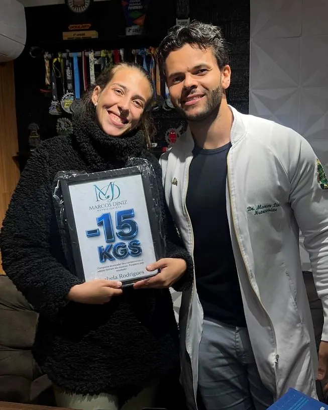 Paciente do Dr. Marcos Diniz recebendo uma placa de resultado